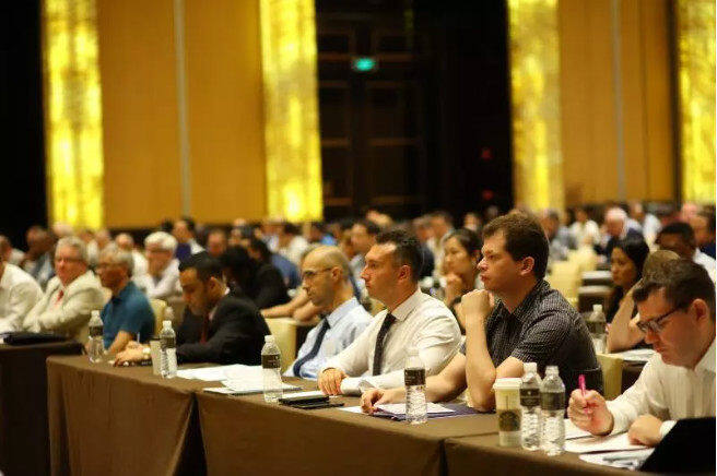 Attendees sit listening at a conference