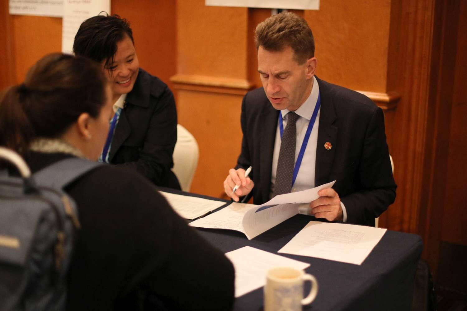 A man interviews a woman across a table